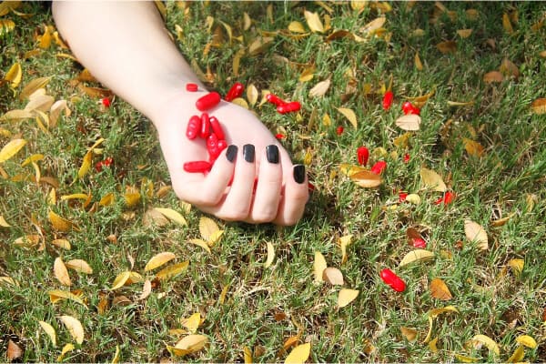 brazo-encima-de-un-cesped-y-con-la-mano-llena-de-pastillas-rojas