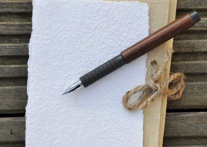 boligrafo tipo madera encima de una hoja para escribir