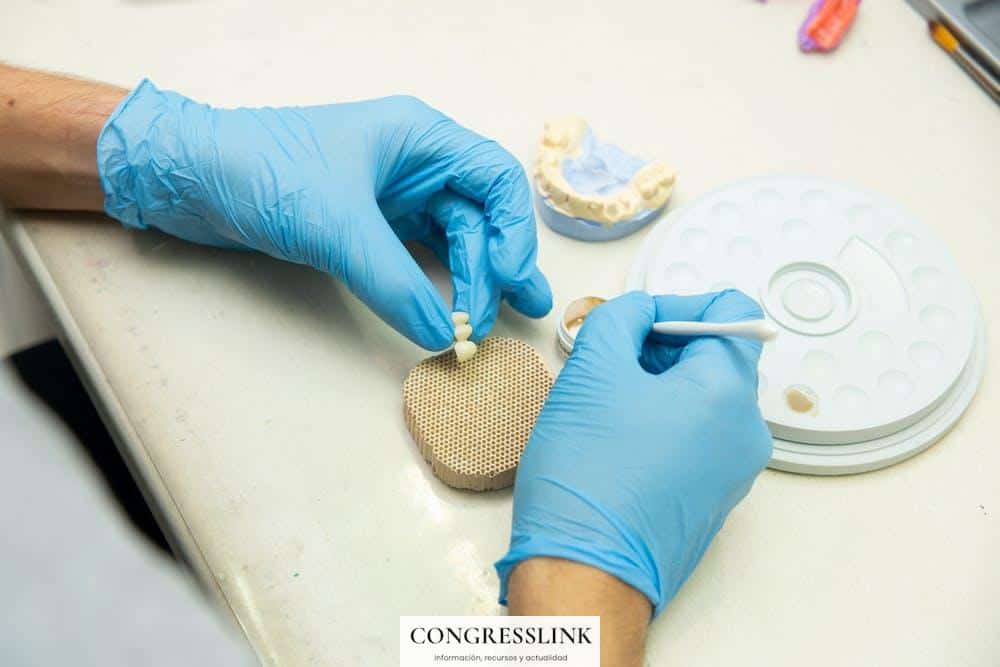 From above of crop anonymous orthodontist in latex gloves creating fake teeth for denture while sitting at table in light dental clinic