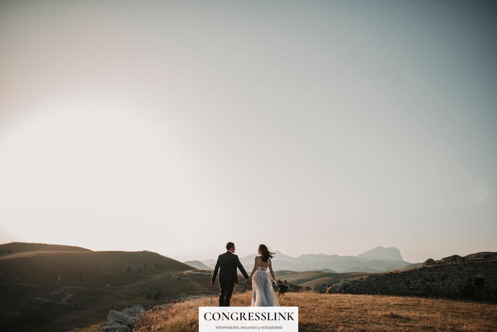 a bride and groom walking on a hill