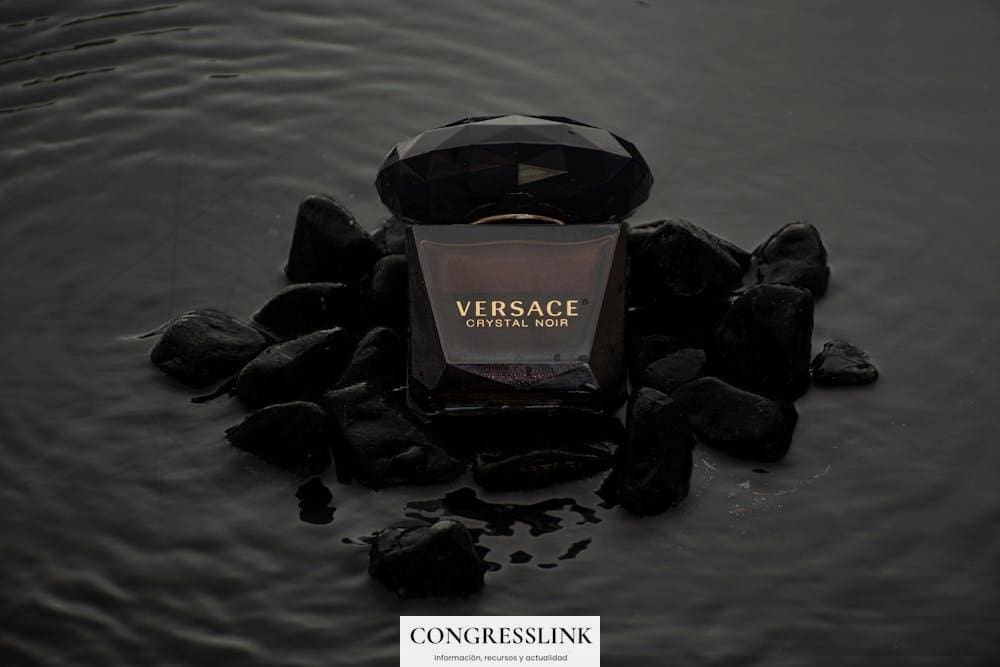 Elegant product shot of Versace Crystal Noir perfume on black stones.